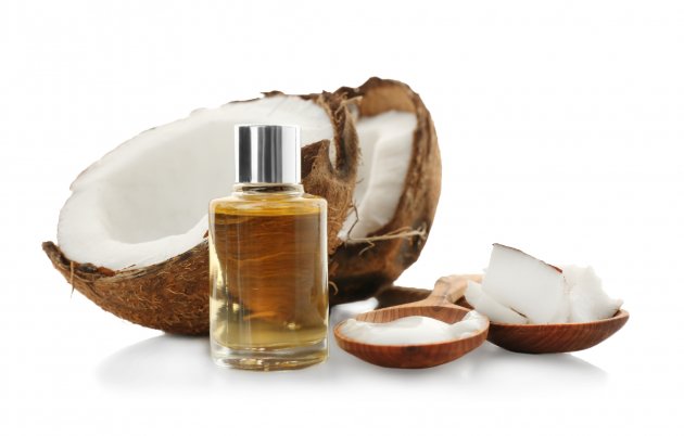 glass bottle with oil near coconut